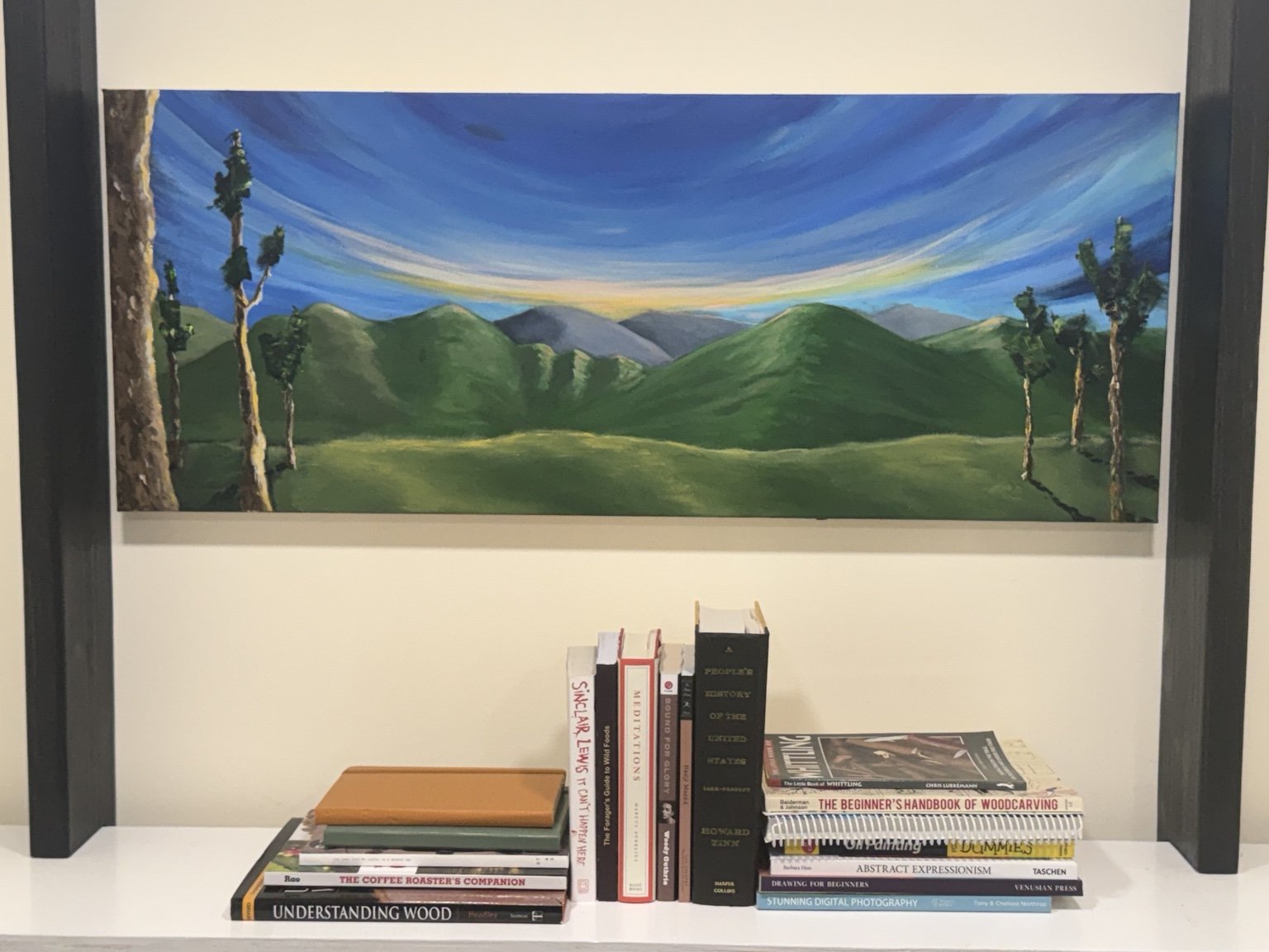 Wide acrylic landscape of green mountains beneath a luminous blue sky